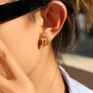 Boucles d'oreilles triple couche en acier inoxydable doré portées par un mannequin au soleil