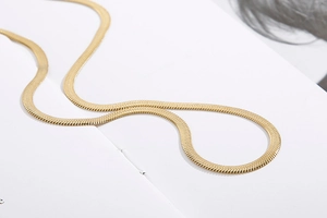 Gros plan d'une chaîne serpent plate dorée avec texture métallique lisse et détaillée
