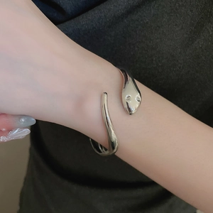 Macro detail of adjustable silver snake-shaped open bracelet on wrist with metallic texture