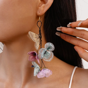 Detail of long floral fringe earrings with embroidered butterfly and tassels on a model