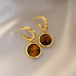 Close-up of vintage gold hoop earrings with brown Tiger's Eye stone in elegant Maillard style