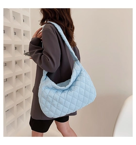 Detail of light blue quilted crossbody bag with diamond stitch patterns on shoulder strap