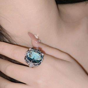 Macro view of oversized square cut blue gemstone ring with micro-pave accents on hand