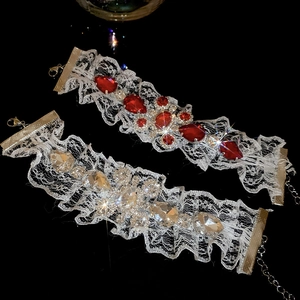 Détail de bracelets en dentelle blanche avec pendentifs en cristal rouge et blanc