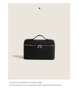 Detailed close-up of a premium black leather vanity bag featuring a smooth top handle