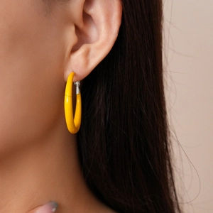 Macro view of bright yellow geometric hoop earrings worn by model for a stylish summer look