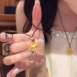 Detail of 24k gold-plated rocking horse pendant with textured finish and black cord