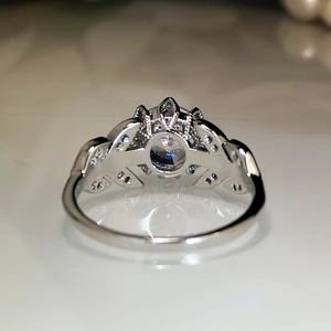 Macro shot of silver crown ring with leaf design and a brilliant round zircon center