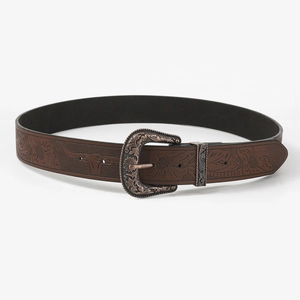 Detail of brown leather belt with embossed floral and bull head patterns and bronze buckle