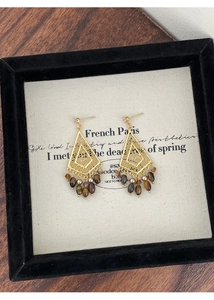 Detail of bohemian gold rhombus earrings with tiger eye stone beads and zircon accents