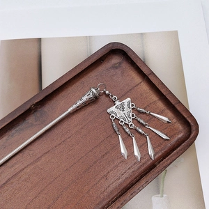 Detailed view of silver ethnic tassel hair pin with vintage floral carvings on wood