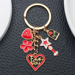 Detail of red enamel heart and rose charms on a gold keychain with star wand and love motifs