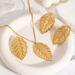 Gros plan d'un ensemble collier et boucles d'oreilles dorés en forme de feuilles