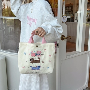 Dettaglio borsa tote in velluto crema con manici rosa e ricamo a gatto
