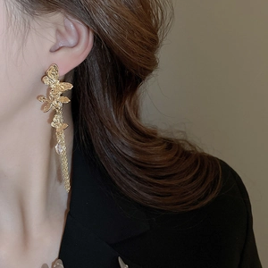 Detail of gold butterfly drop earrings with textured metal wings and tassels on model