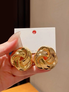 Detailed view of chunky gold twisted knot earrings with polished metallic finish
