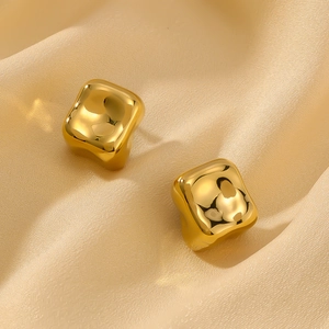 Golden irregular square hollow earrings with glossy polished finish on silk fabric