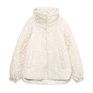 Detailed view of floral quilted stitching on a cream padded jacket with snap buttons