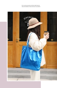 Bright blue metallic tote bag with wrinkled texture shown on model in street style view