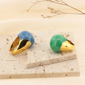 Detail of blue and green marble enamel rings with gold finish on a minimal stone tray