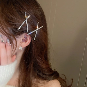 Detail of silver crisscross hair clips with sparkling rhinestones worn by a model