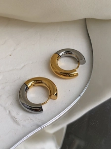 Detailed shot of two-tone gold and silver chunky hoop earrings on a white plate
