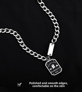 Detail view of silver cuban chain with black shield pendant and engraved metal tag