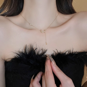 Détail du collier doré avec pendentifs lune et étoile en zircons sur le clavicule