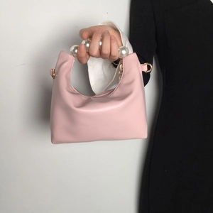 Detail of pink soft leather handbag featuring an elegant pearl handle and gold hardware