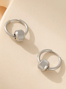 Detail view of silver hoop earrings with geometric diamond-patterned textured slide beads