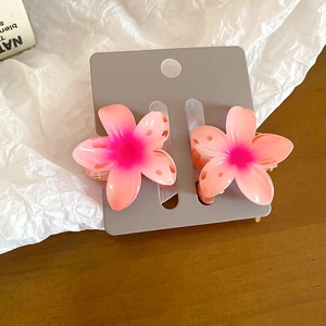 Detail of pink gradient sunflower hair claws on display card with wood background