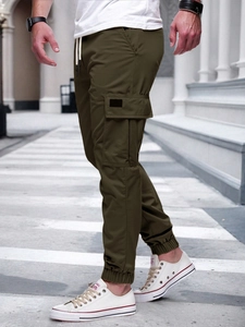 Detail of dark olive cargo pants featuring multi-pocket design and straight leg drawstring waist