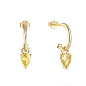 Macro shot of S925 sterling silver C-shaped gold earrings with pear-cut yellow gemstones
