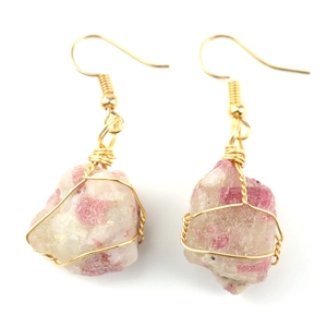 Macro detail of handmade gold wire-wrapped raw pink tourmaline crystal earrings