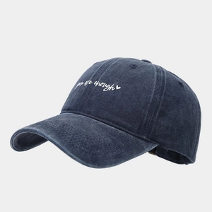 Gros plan de la broderie blanche 'you are enough' sur la casquette en coton bleu foncé
