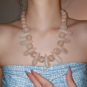 Close-up of bohemian resin necklace with marbled beads and drop pendants on model neck