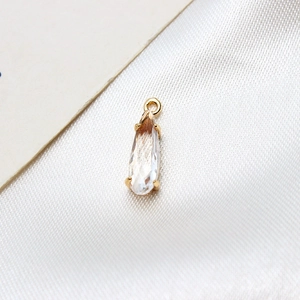Macro shot of a teardrop-shaped glass pendant in a gold-plated copper claw setting