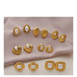 Detail shot of vintage gold stud earrings with pearls on silk fabric display