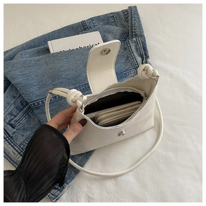Detailed top view of a white leather shoulder bag featuring a sleek magnetic closure and strap