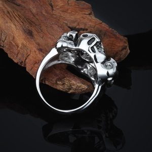 Close-up of silver skull ring on rustic wood with high contrast metal texture