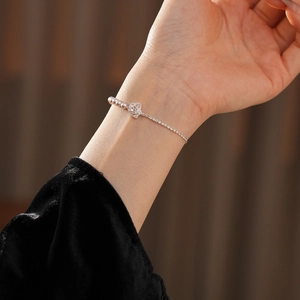 Détail d'un élégant bracelet perles et fleurs zircon avec texture argentée et perles roses