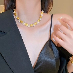 Close-up of gold-plated necklace with faux pearl flowers worn on a neck model