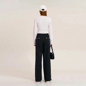 Detail of wide-leg cargo pants with flap pockets, metal buckles, and adjustable drawstrings