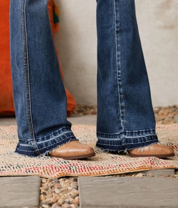 Detail of distressed bell-bottom jeans with frayed hems and vintage wash denim texture