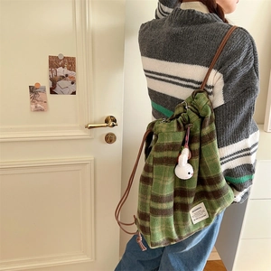 Detail of green plaid woolen drawstring backpack with cute white rabbit plush charm