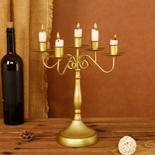 Detailed view of 5-arm gold metal candelabra with burning white candles on wooden table