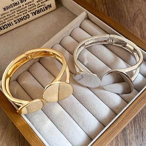 Minimalist gold and silver layered oval bracelets displayed in a wooden jewelry gift box