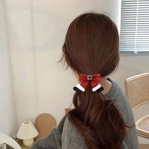 Christmas red bow hair scrunchie with Santa boots pendant worn on a brown ponytail