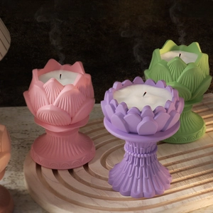 Three lotus-shaped candle holders in pink, purple, and green on a wooden display
