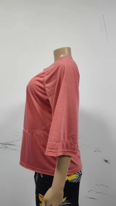 Detailed side view of coral orange crewneck top featuring stylish flared five-point sleeves